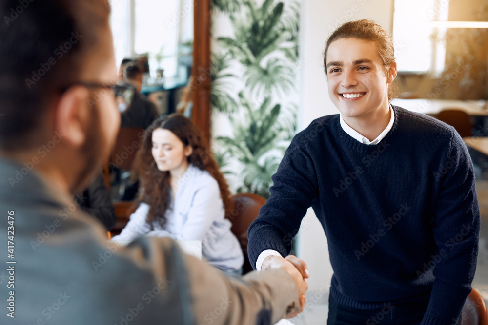Portrait of cheerful young manager handshake with new employee. Portrait of cheerful young manager handshake with new employee.