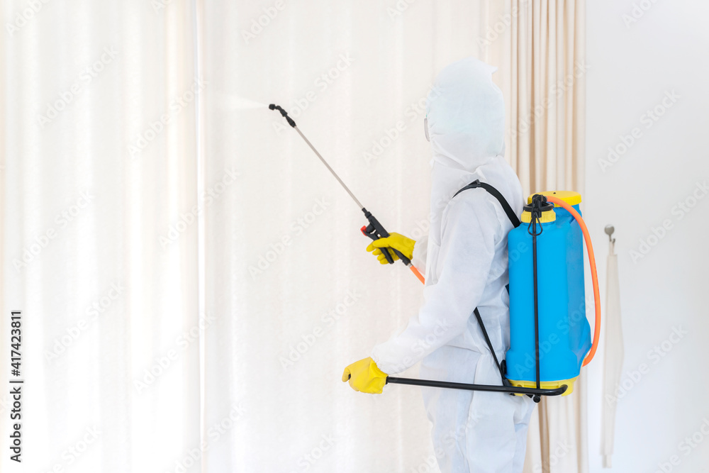 Male worker spraying disinfectant to house window