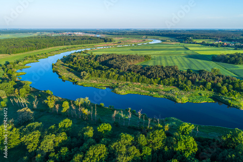 The majestic river meanders between green areas. The blue color contrasts with the greens of fields and meadows. 