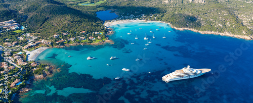 View from above, stunning aerial view of the Grande Pevero beach with boats and luxury yachts sailing on a turquoise, clear water. Sardinia, Italy. © Travel Wild