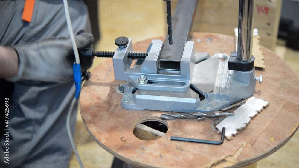 Worker man clamps a square metal profile pipe in a vice in his workshop Worker man clamps a square metal profile pipe in a vice in his workshop