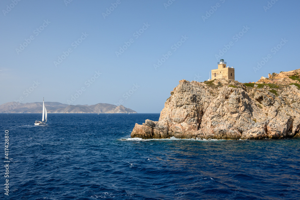 The old lighthouse on rocks at the entrance to the harbor bay. Ios island, Cyclades, Greece The old lighthouse on rocks at the entrance to the harbor bay. Ios island, Cyclades, Greece