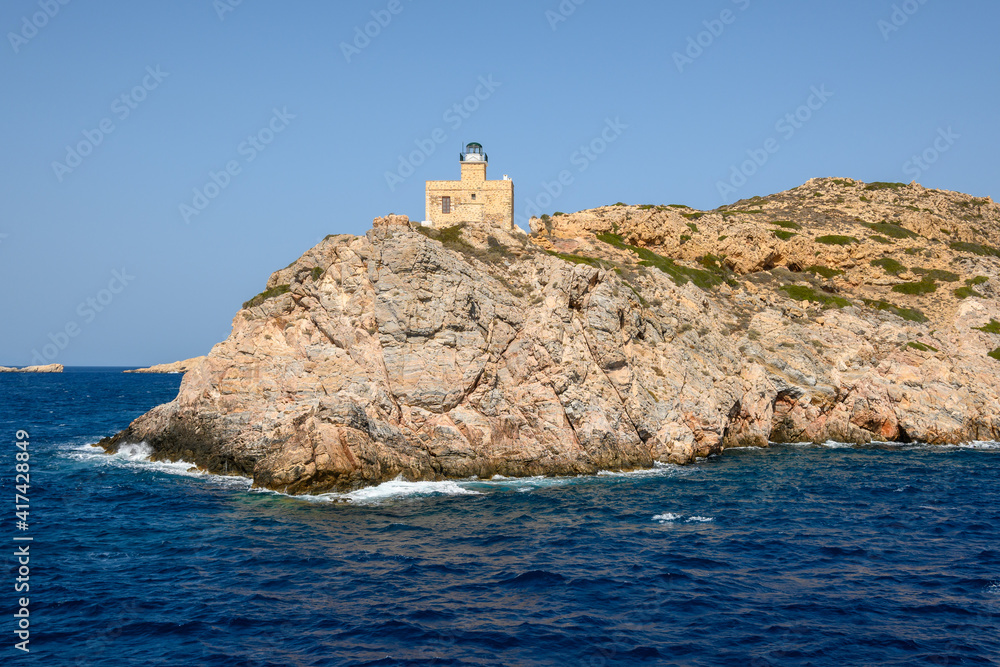 The old lighthouse on rocks at the entrance to the harbor bay. Ios island, Cyclades, Greece