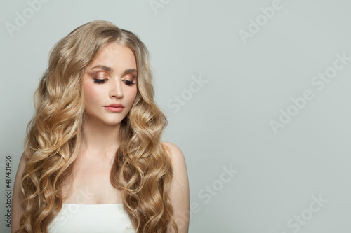Pretty fashion model woman with long healthy blonde hair on white background