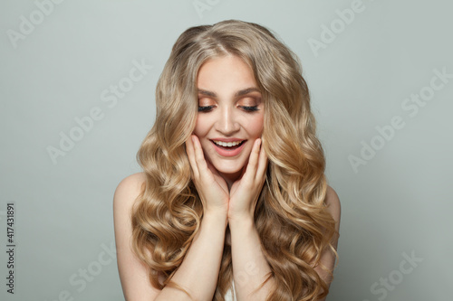 Happy surprised woman with blonde hair on white background