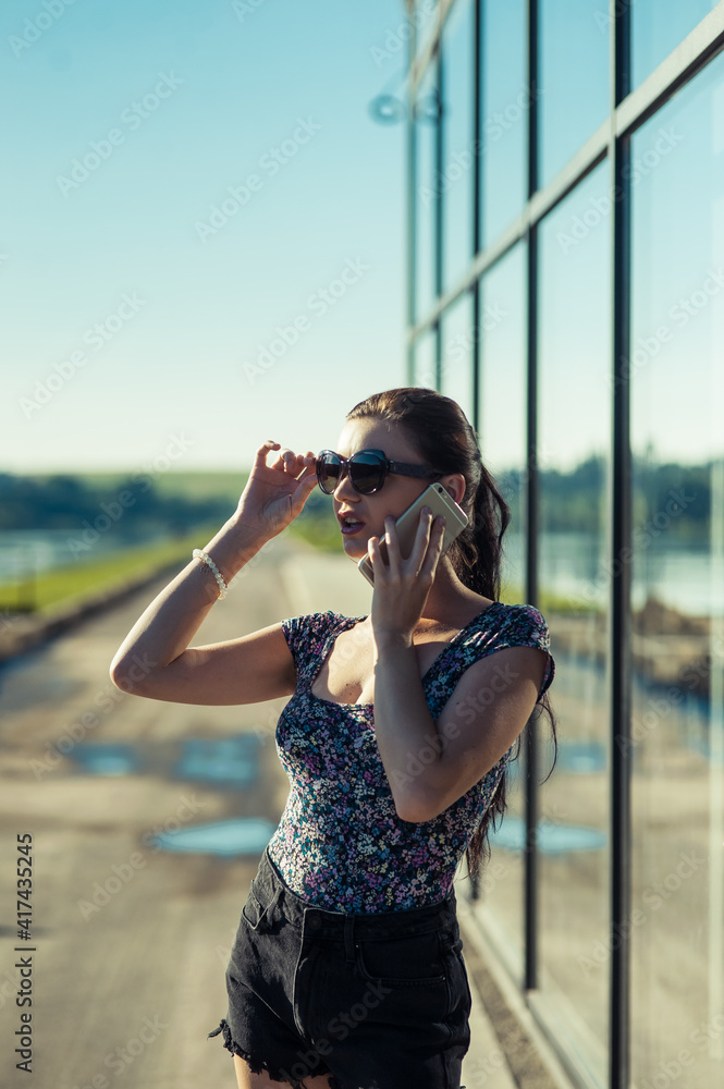 Very sexy girl talking on the phone.girl with long legs near a glass structure.Very sexy girl talking on the phone.