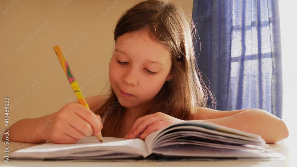 Cute child girl is drawing with a pencil in her sketchbook during stay at home Cute child girl is drawing with a pencil in her sketchbook during stay at home
