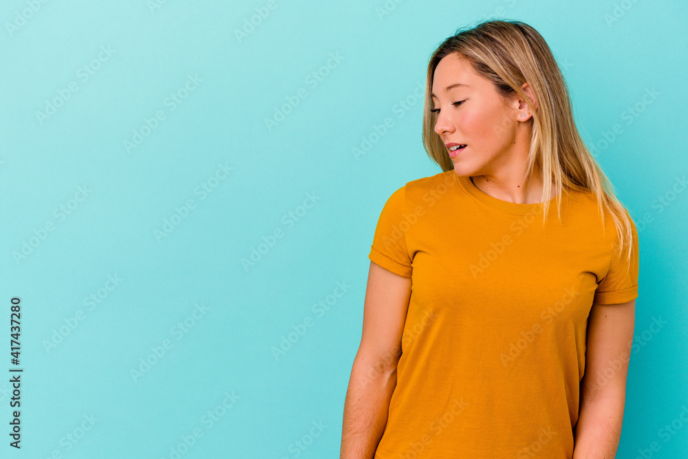 Young mixed race woman isolated on blue background being shocked because of something she has seen. Young mixed race woman isolated on blue background being shocked because of something she has seen.