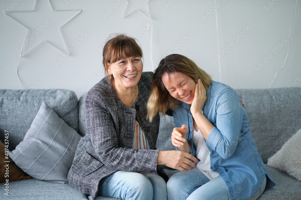 elderly mother and daughter having fun enjoying talk sit on sofa in modern living room. talking to elderly concept. Portrait of elderly mother and middle aged daughter smiling together