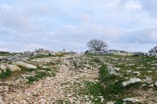 antique road among ancient ruins leads to a modern city on the horizon