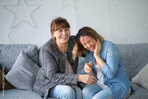 elderly mother and daughter having fun enjoying talk sit on sofa in modern living room. talking to elderly concept. Portrait of elderly mother and middle aged daughter smiling together