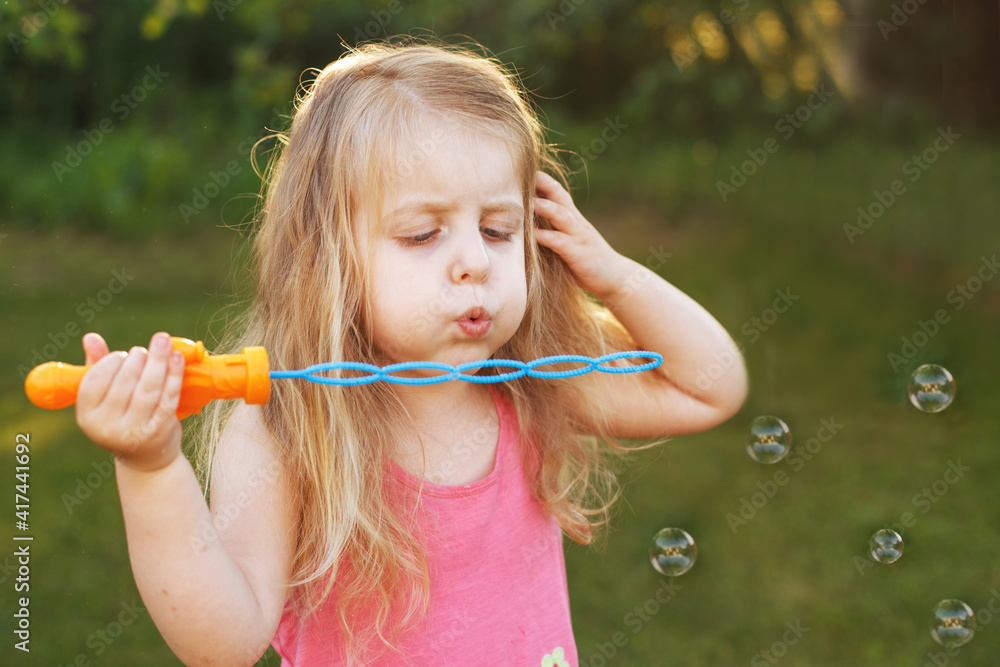 Cute little girl is blowing soap bubbles Cute little girl is blowing soap bubbles