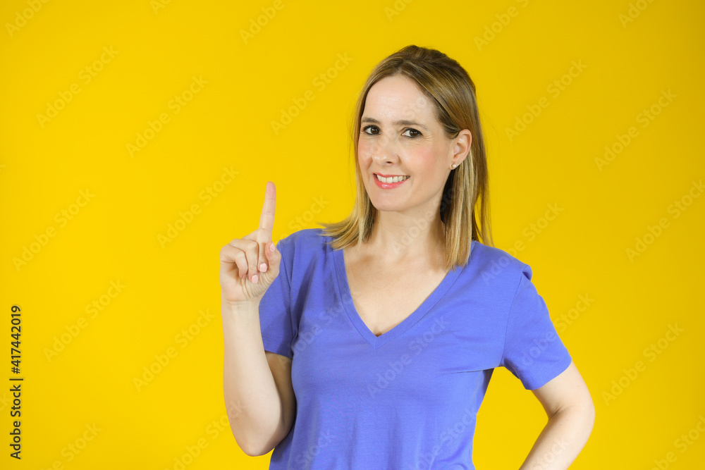 Portrait of beautiful young woman pointing up over yellow background. Portrait of beautiful young woman pointing up over yellow background.