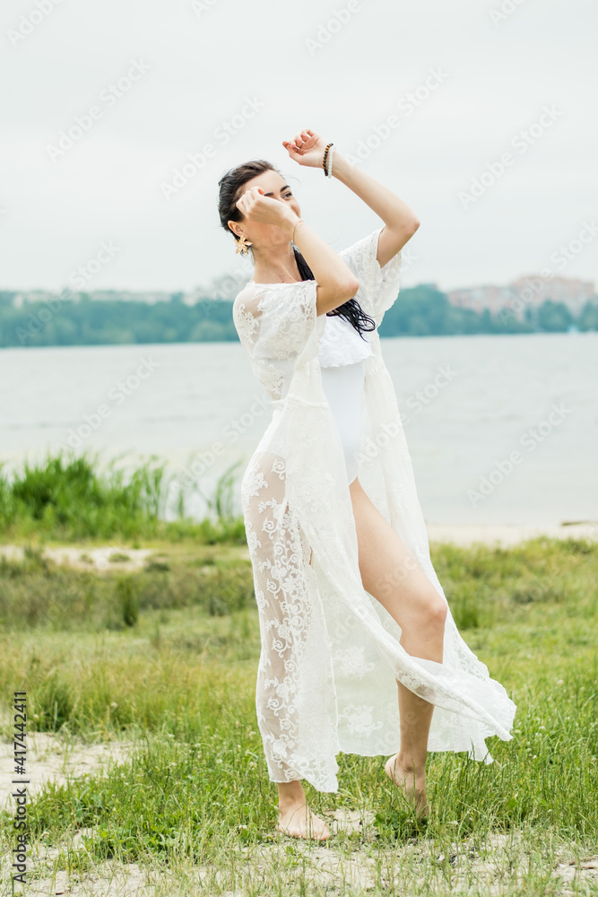 Sexy girl in a white dress on a background of the lake.