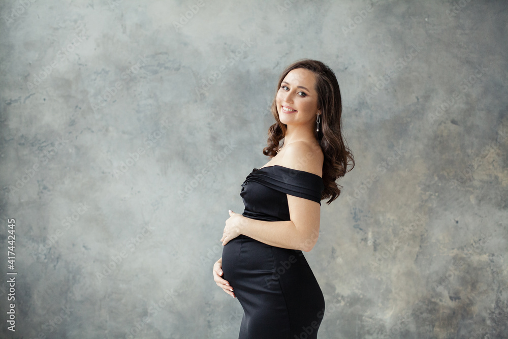 Pregnant woman portrait. Beautiful lady wearing black dress smiling Pregnant woman portrait. Beautiful lady wearing black dress smiling