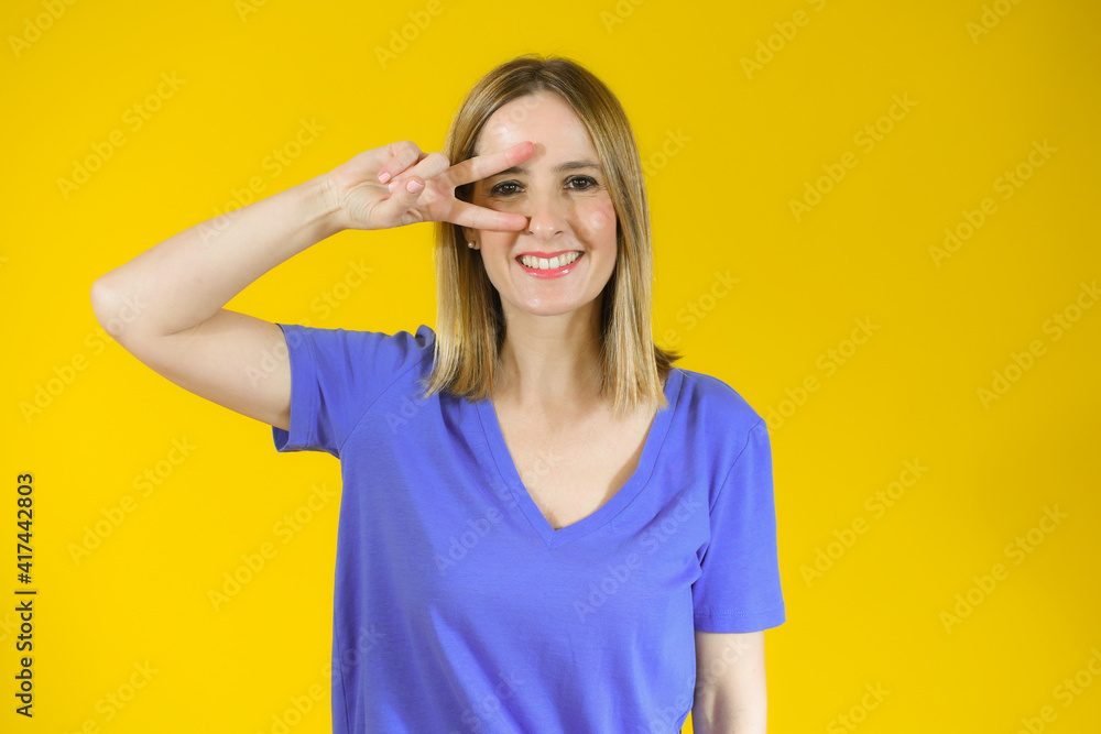 Beautiful young woman happy and excited expressing winning gesture. Successful pretty woman celebrating victory, triumphant over yellow background Beautiful young woman happy and excited expressing winning gesture. Successful pretty woman celebrating victory, triumphant over yellow background