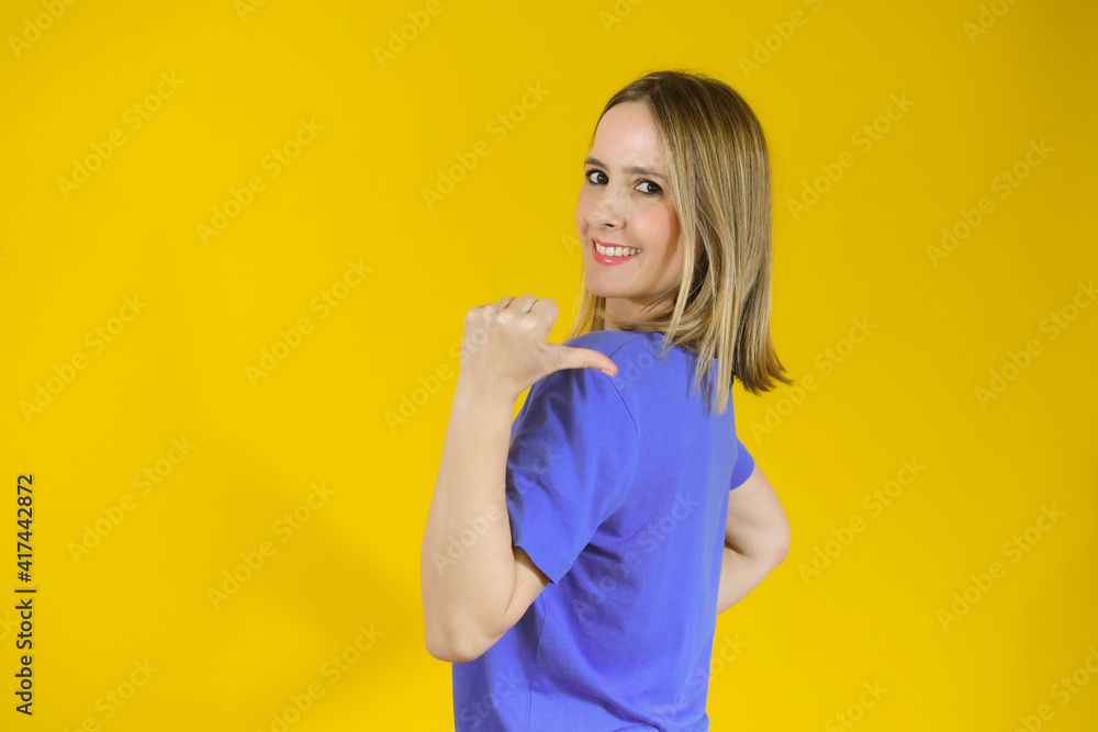 Young woman over isolated yellow background pointing finger to the side Young woman over isolated yellow background pointing finger to the side