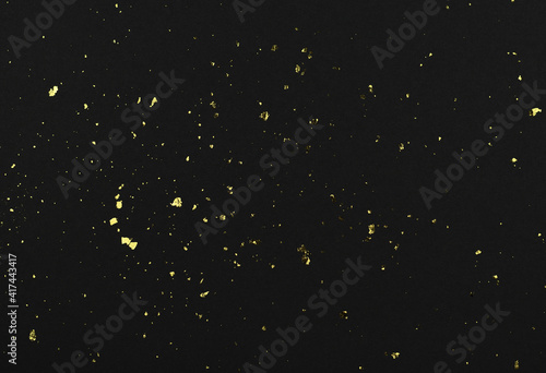 Gold flakes of potal on black textured paper photo