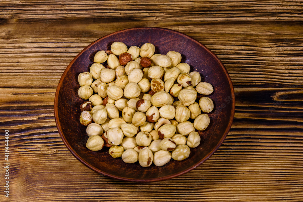 Ceramic plate with peeled hazelnuts on a wooden table Ceramic plate with peeled hazelnuts on a wooden table