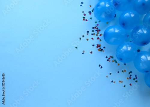Blue balls on a light blue background. Place for text. Holidays. Small stars next to the balls. Balls in the upper right corner. Layout. View from above. 
