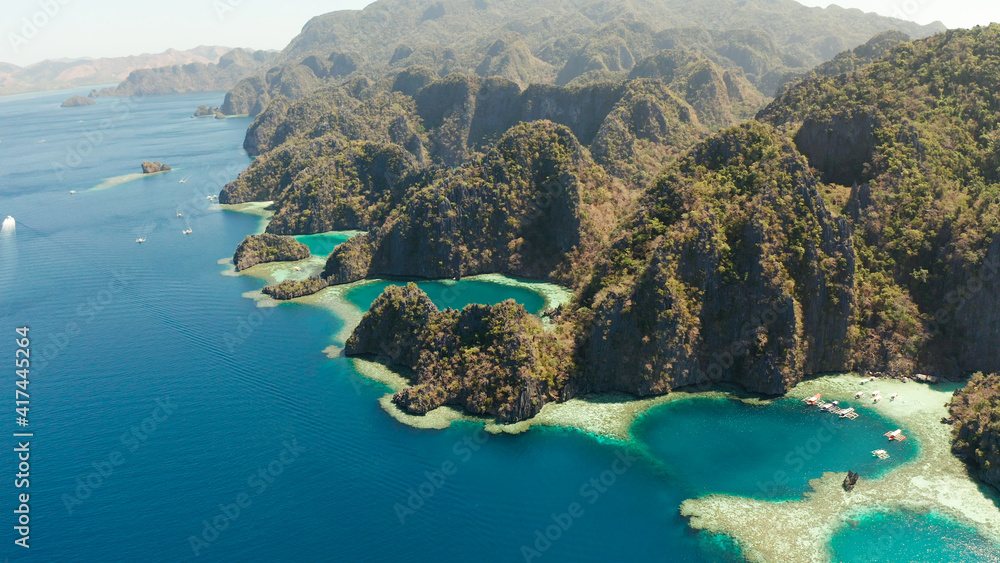 Tourist boats around the beautiful big and small lagoons, aerial view. lagoon, mountains covered with forests.coves with blue water among the rocks. Seascape, tropical landscape. Palawan, Philippines