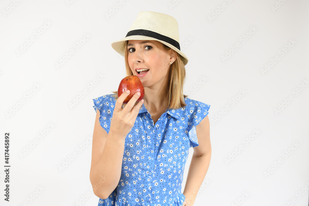 Beautiful young woman in straw hat eating an apple Beautiful young woman in straw hat eating an apple