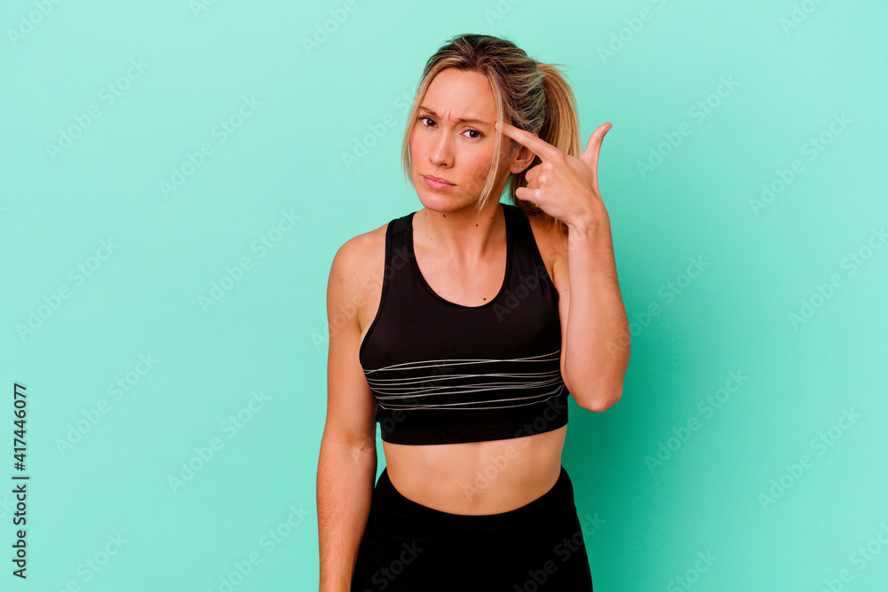 Young caucasian sport woman isolated on blue background showing a disappointment gesture with forefinger. Young caucasian sport woman isolated on blue background showing a disappointment gesture with forefinger.