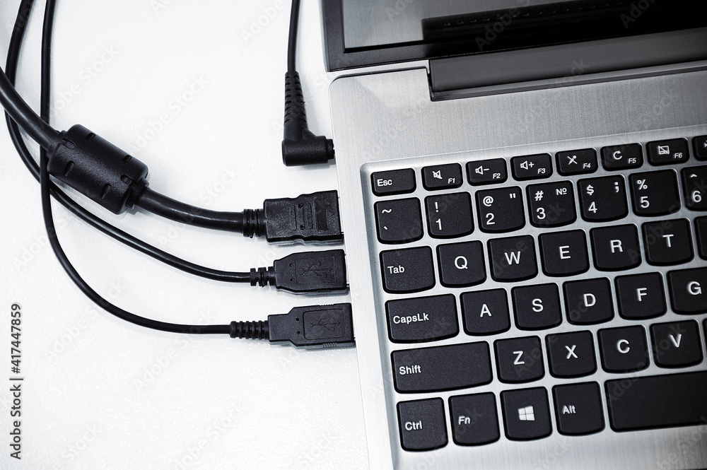 Gray laptop with connected wires in interface on white table. View from above. Gray laptop with connected wires in interface on white table. View from above.