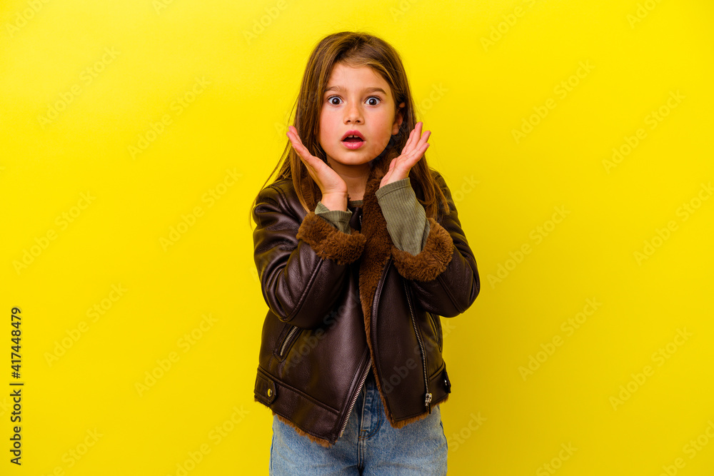 Little caucasian girl isolated on yellow background surprised and shocked. Little caucasian girl isolated on yellow background surprised and shocked.