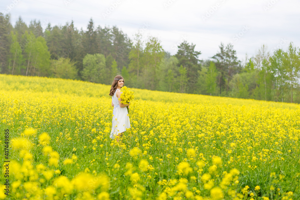 Beautiful girl in a rapeseed field. A child in a blooming field with yellow flowers. Plantation of yellow flowers Beautiful girl in a rapeseed field. A child in a blooming field with yellow flowers. Plantation of yellow flowers