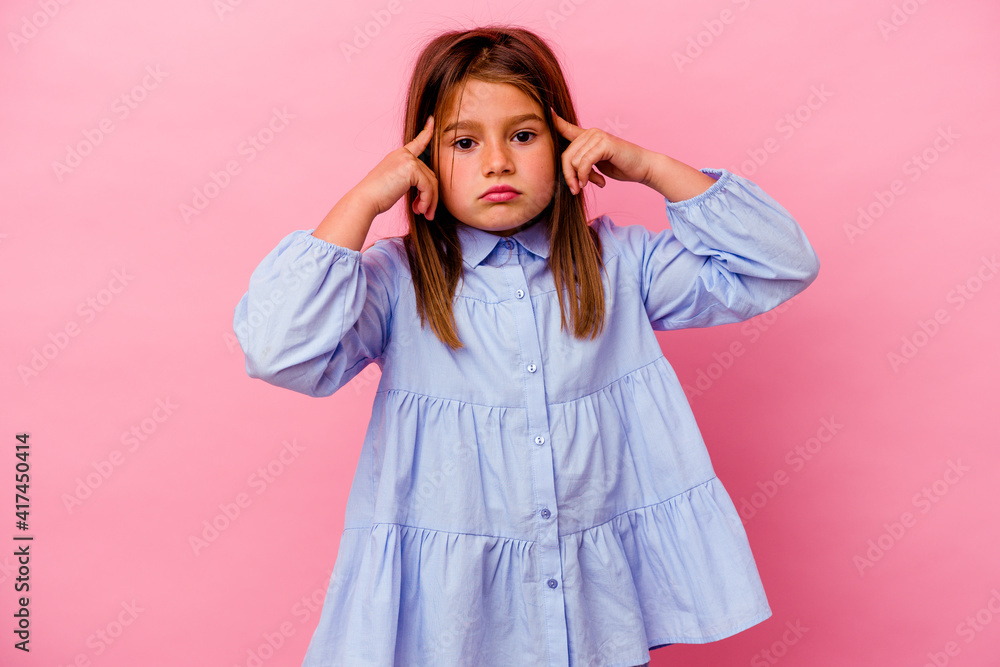 Little caucasian girl isolated on pink background focused on a task, keeping forefingers pointing head. Little caucasian girl isolated on pink background focused on a task, keeping forefingers pointing head.