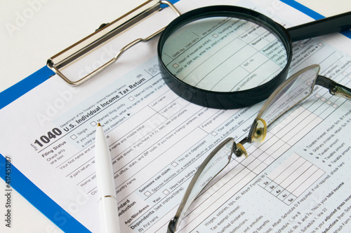 Tax form 1040 with pen  eyeglasses and magnifying glass