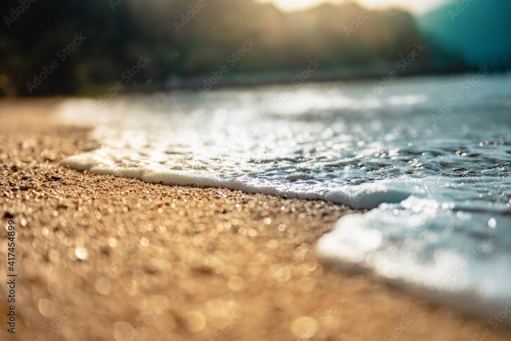 Close-up soft wave of the sea on the sandy beach in morning with sunlight effect. Close-up soft wave of the sea on the sandy beach in morning with sunlight effect.