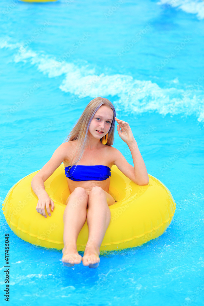 A beautiful young girl lies on an inflatable mattress in the summer water park. Girl swims in the summer pool. Vacation at sea