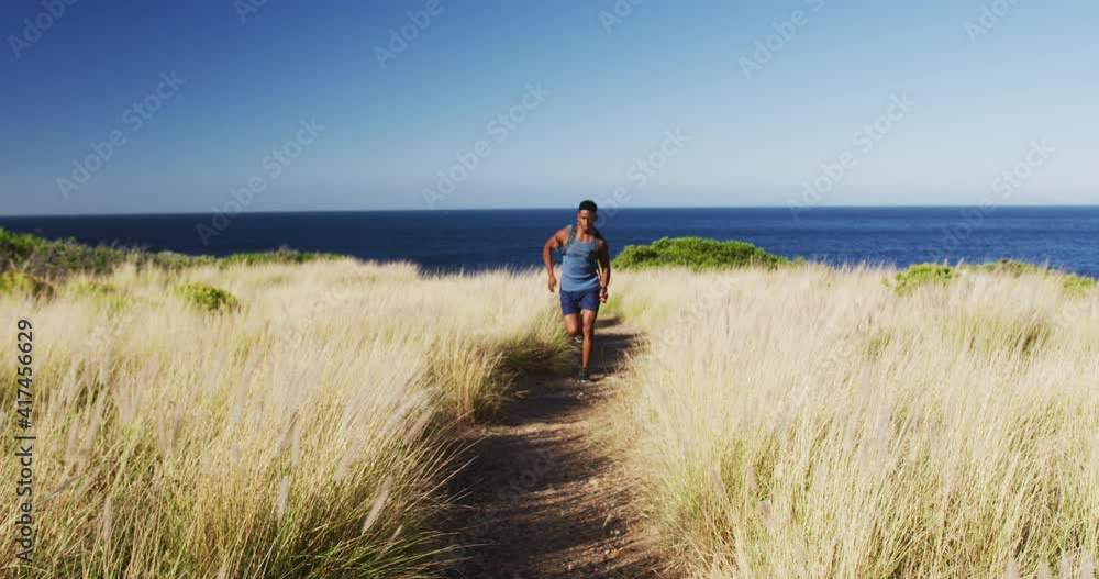 African american man cross country running in countryside on a coast African american man cross country running in countryside on a coast