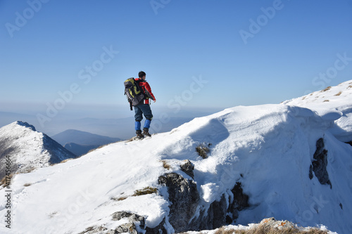 Man on top of snowy mountain. Lonely mountaineer get rest on snowy mountain high above the clouds