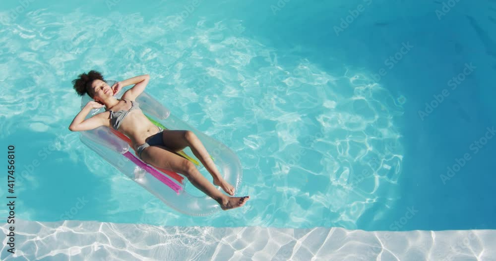 Mixed race woman having fun sunbathing on inflatable in swimming pool Mixed race woman having fun sunbathing on inflatable in swimming pool