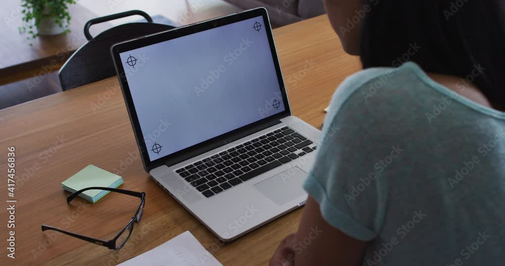 Mixed race gender fluid person sitting at desk working from home using a laptop Mixed race gender fluid person sitting at desk working from home using a laptop