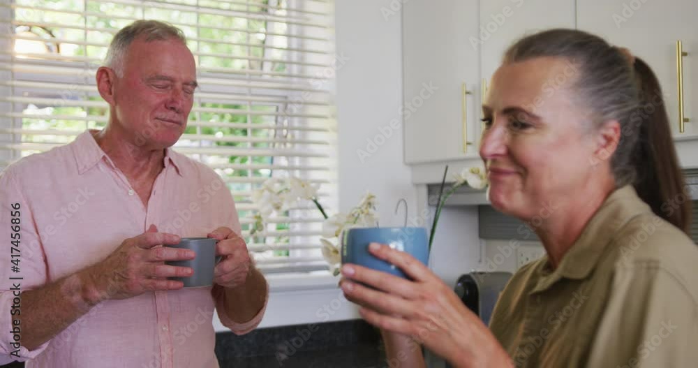 Caucasian senior couple drinking coffee together in the kitchen at home Caucasian senior couple drinking coffee together in the kitchen at home