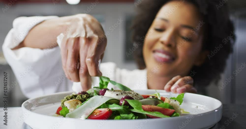 African american female chef garnishing dish and similing in restaurant kitchen African american female chef garnishing dish and similing in restaurant kitchen