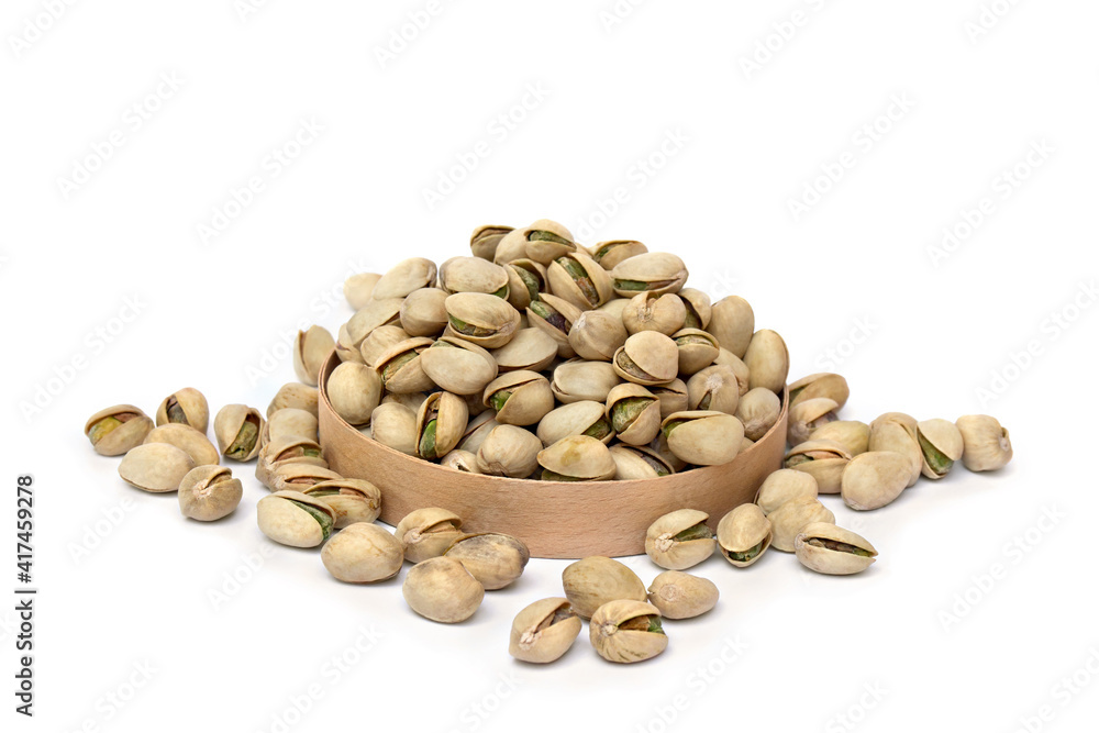 Roasted and salted pistachios in shell in wooden circle box on a white background Roasted and salted pistachios in shell in wooden circle box on a white background