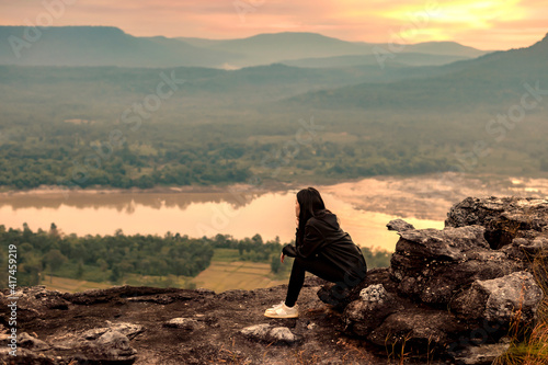 Woman sitting on a rock looking at view,  Ubon Ratchathani, Isan, Thailand photo