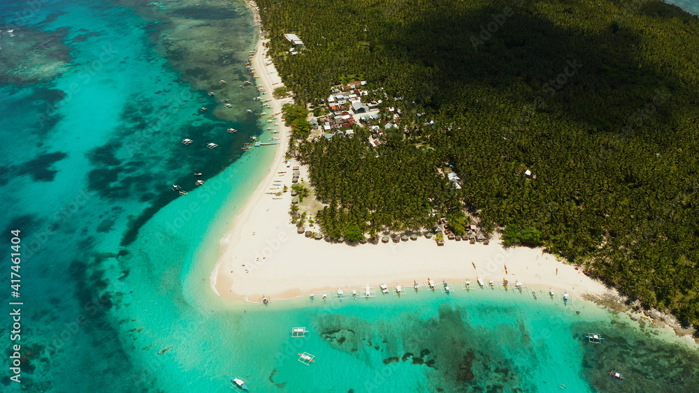 Sandy beach with tourists, palm trees and turquoise water on the island of Daco, Philippines, aerial view. Summer and travel vacation concept