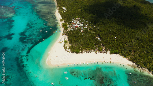 Sandy beach with tourists, palm trees and turquoise water on the island of Daco, Philippines, aerial view. Summer and travel vacation concept
