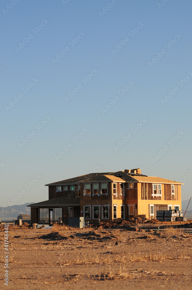 Obraz premium Partially completed two-story home in a desert lot, representing suburban housing construction, real estate development, and residential infrastructure expansion in arid environments