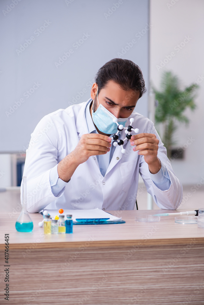 Young male chemist teacher sitting in the classroom Young male chemist teacher sitting in the classroom