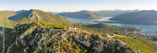 Aerial panorama drone shot of stone fortress Wall of Ston on top of hill view of Mali Ston in Croatia summer sunrise