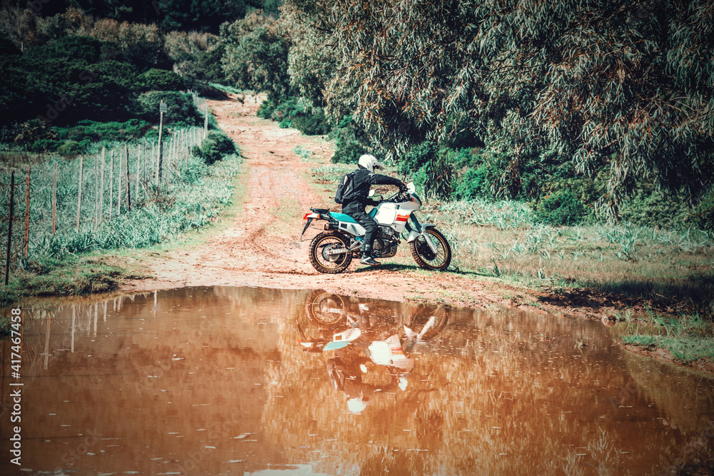 Biker and his adventure bike reflected in a puddle Biker and his adventure bike reflected in a puddle
