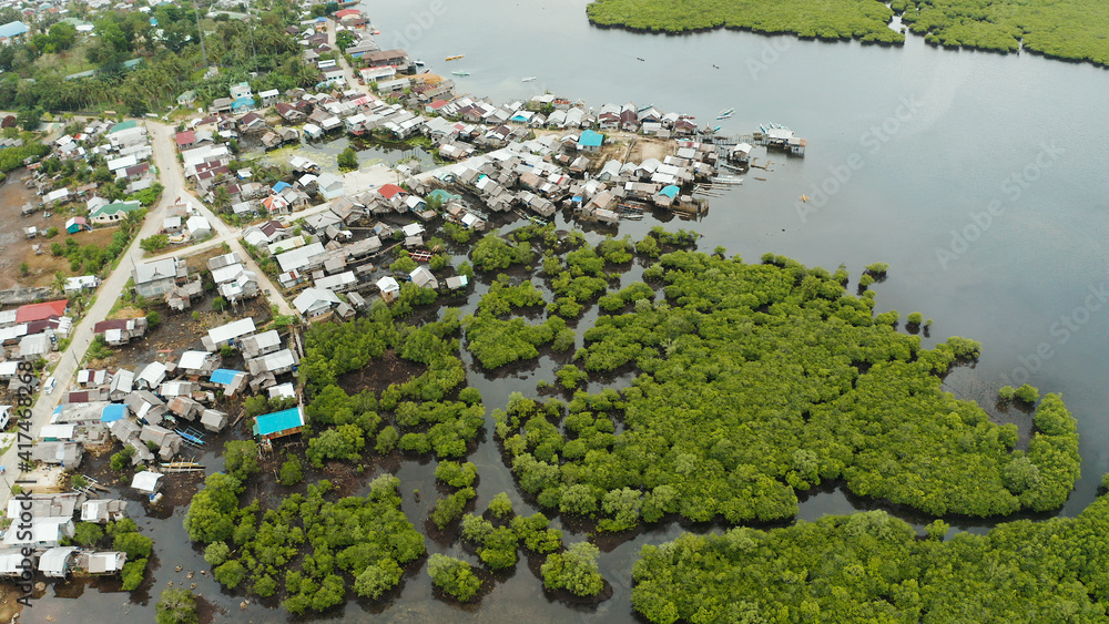 Town in wetlands and mangroves on the ocean coastline from above. Siargao island, Philippines.