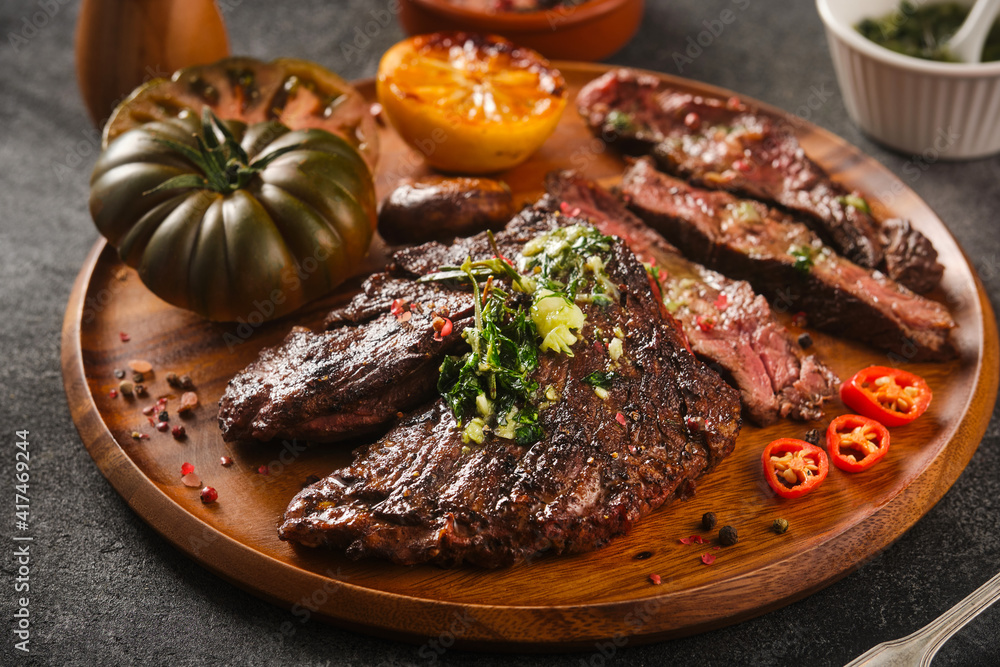 Hanger steak bbq with souce chimichurri on wooden plate, close up Hanger steak bbq with souce chimichurri on wooden plate, close up